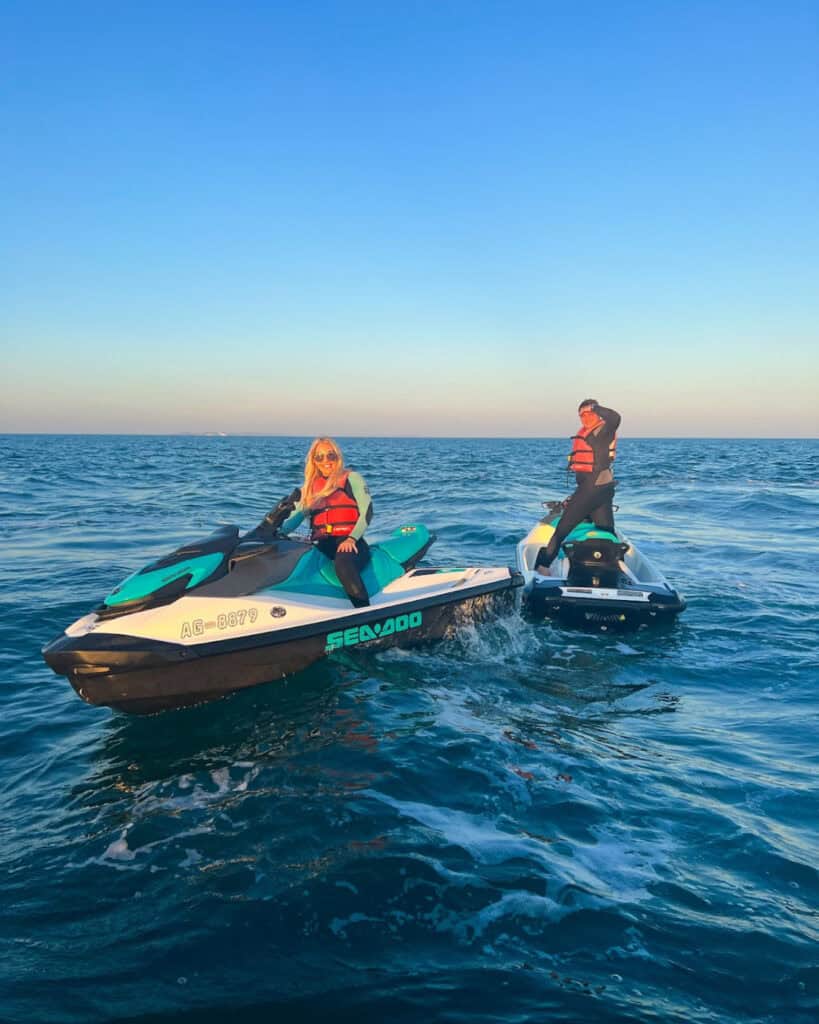 Two people riding jet skis on the ocean during daytime.