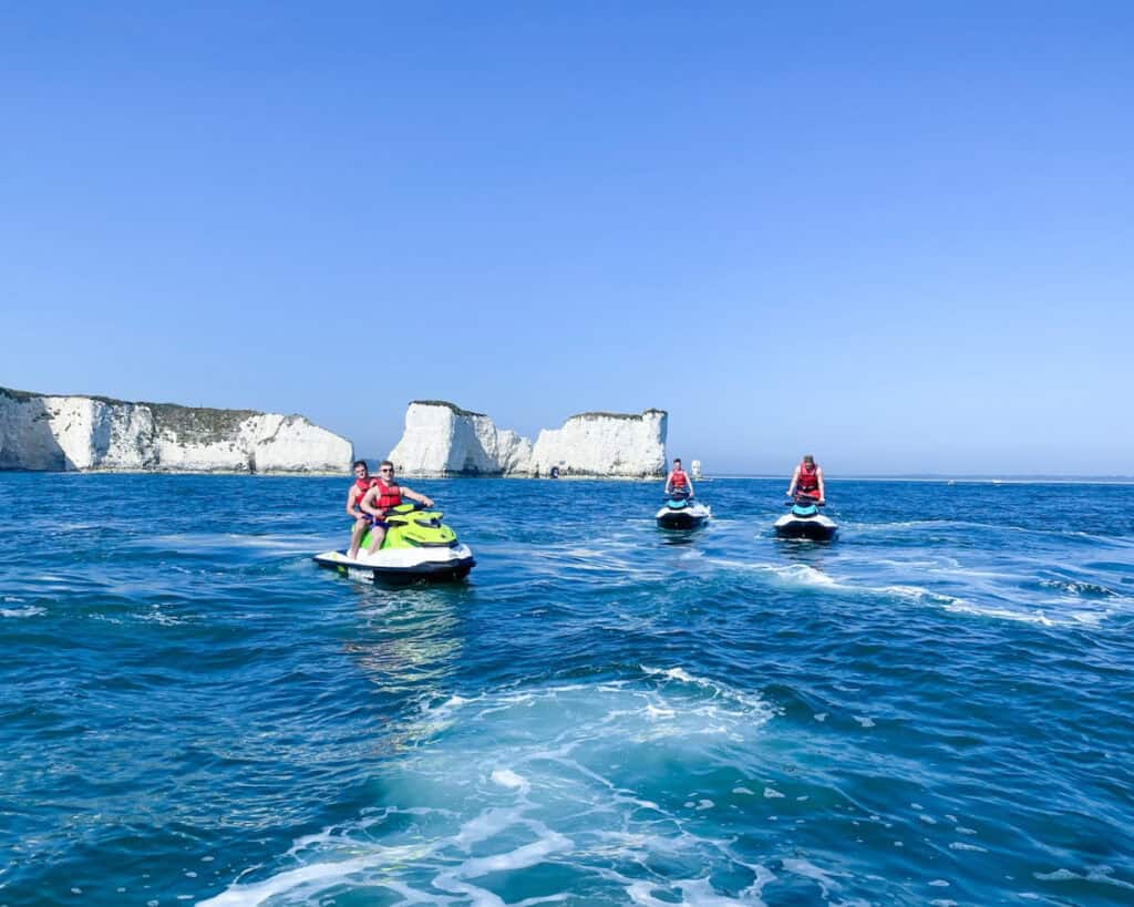 Jet skis riding near white cliffs on the coast.